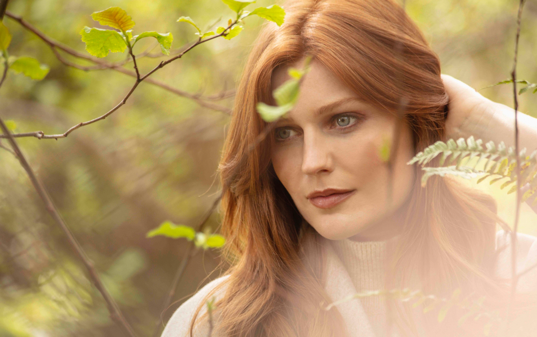 Red haired lady stands in forest 