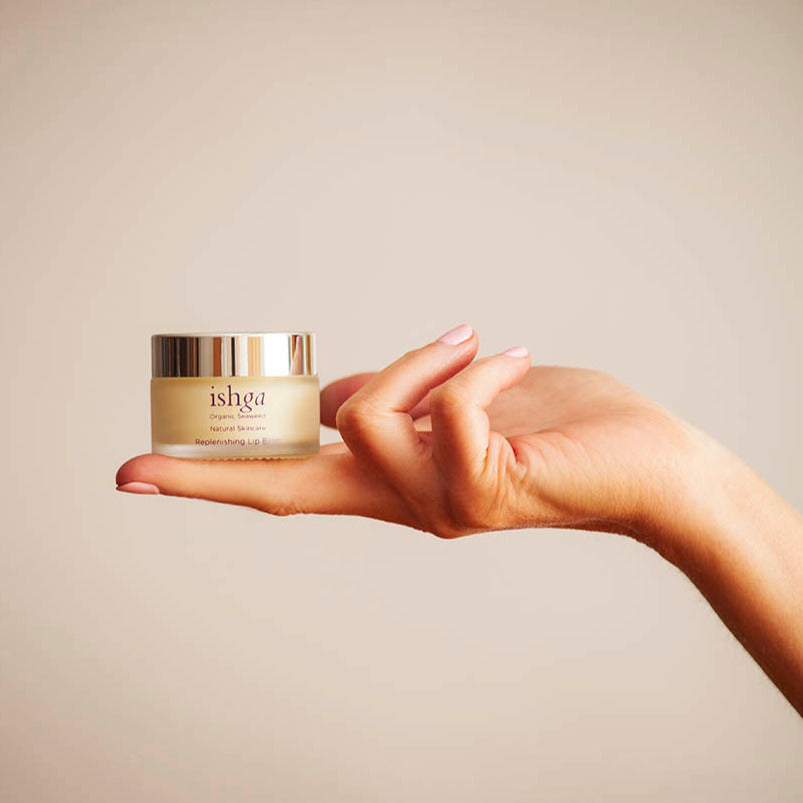 Lip balm held up in hand against neutral background