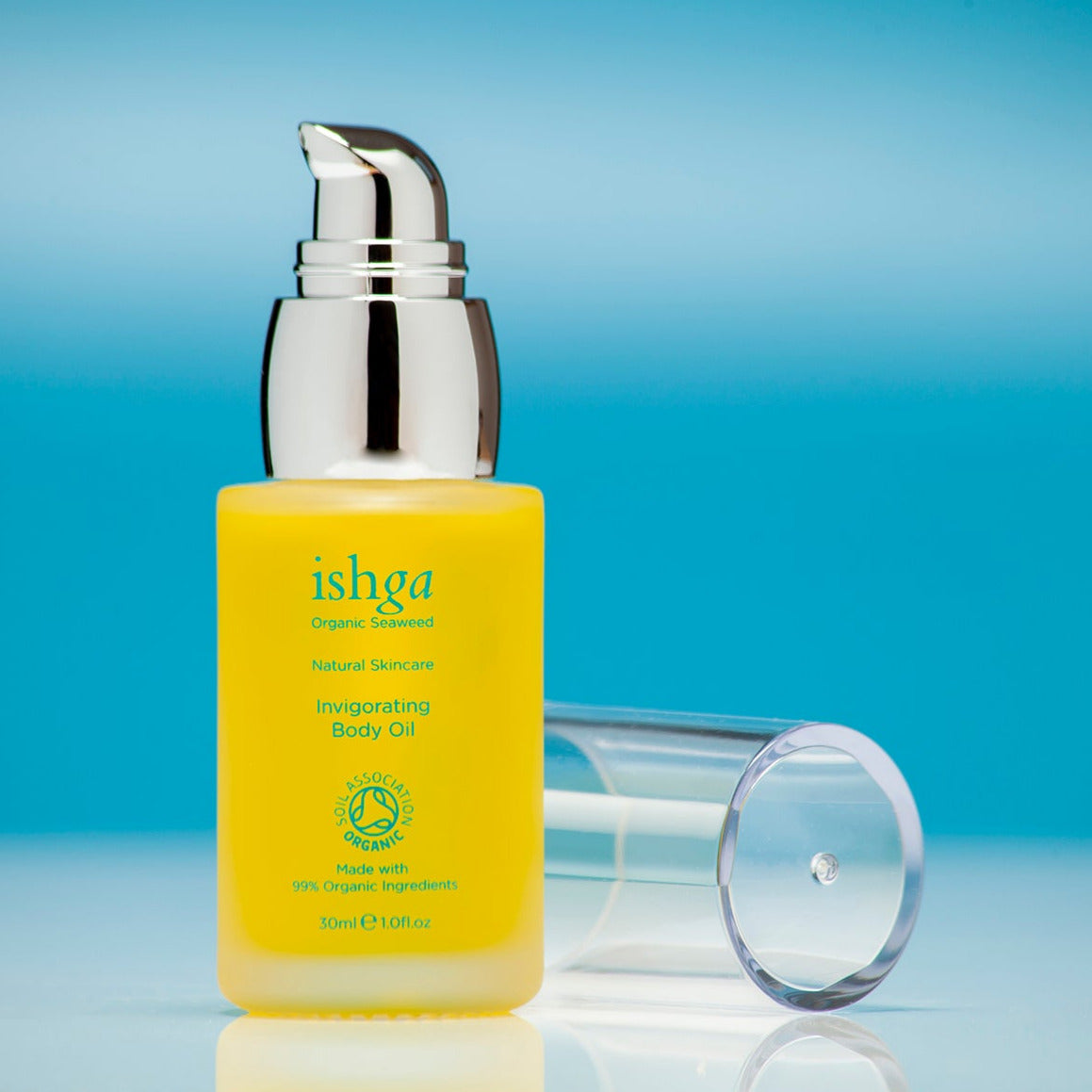 Glass bottle of ishga Invigorating Body Oil with its lid next to it