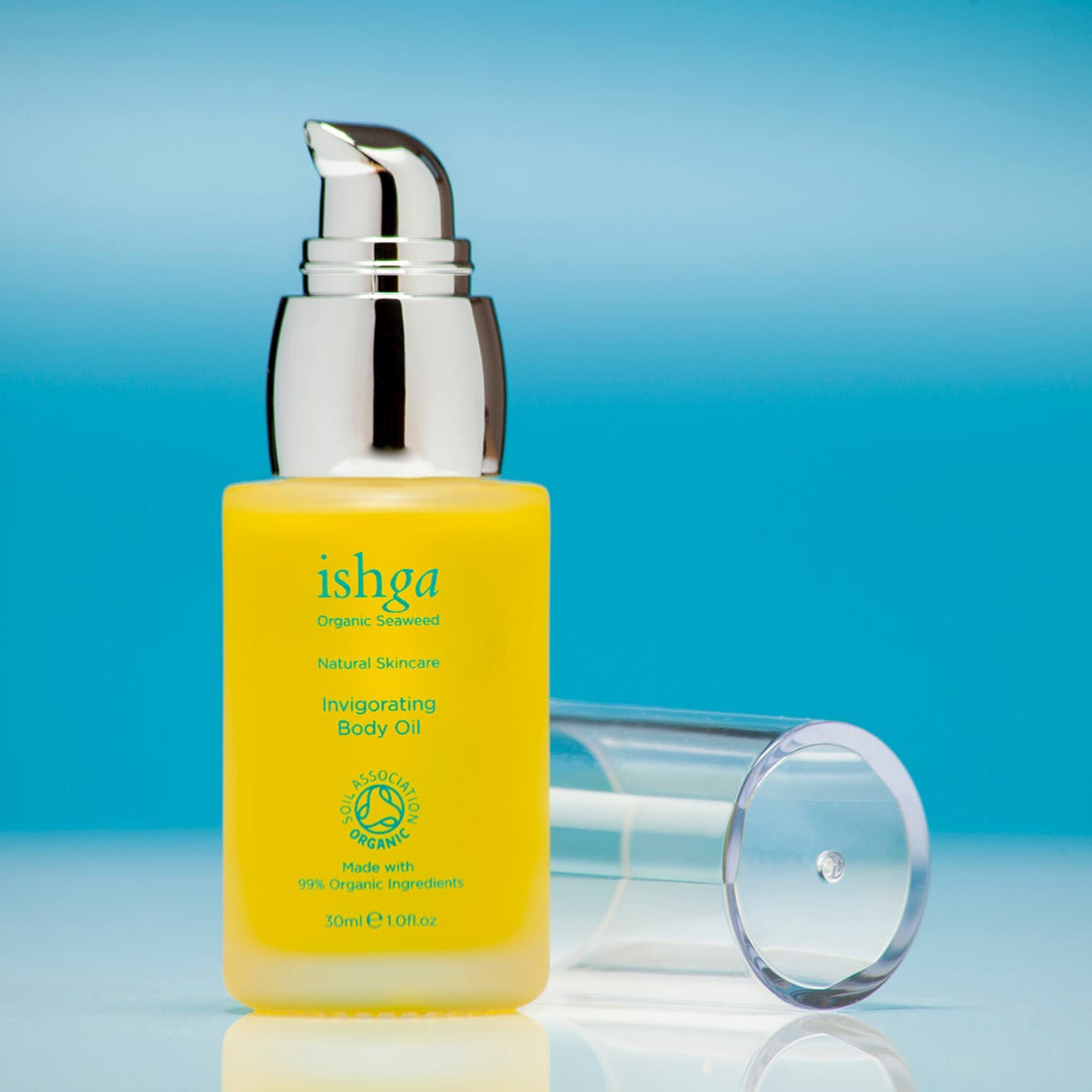 Glass bottle of ishga Invigorating Body Oil with its lid next to it