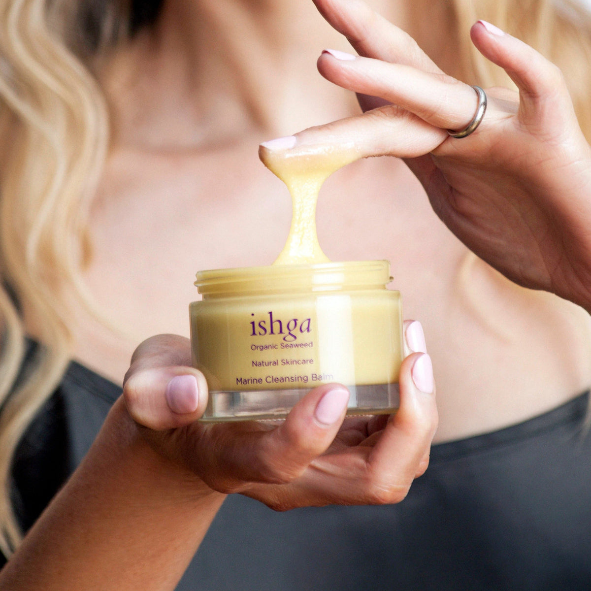 Lady holding a jar of Marine Cleansing Balm with fingers showing texture