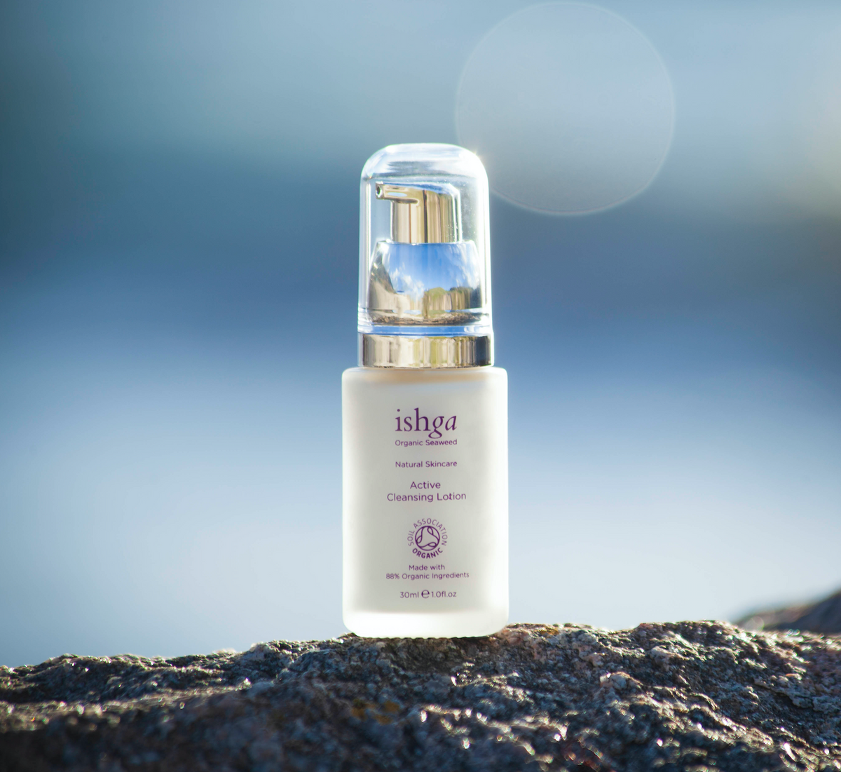 Small bottle of ishga Active Cleansing Lotion on a rock outside