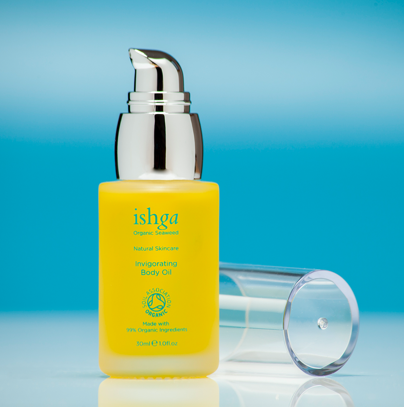 Small glass bottle of ishga Invigorating Organic Body Oil with its lid next to it