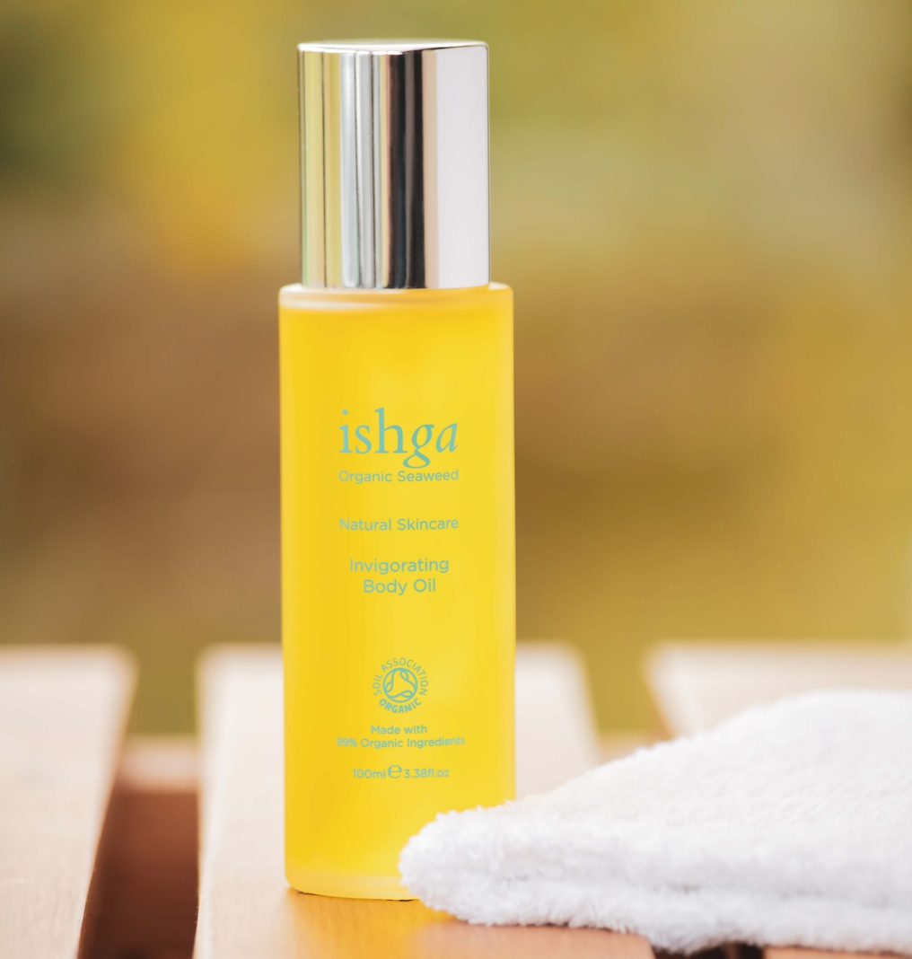 Bottle of ishga Invigorating Organic Body Oil next to a white towel